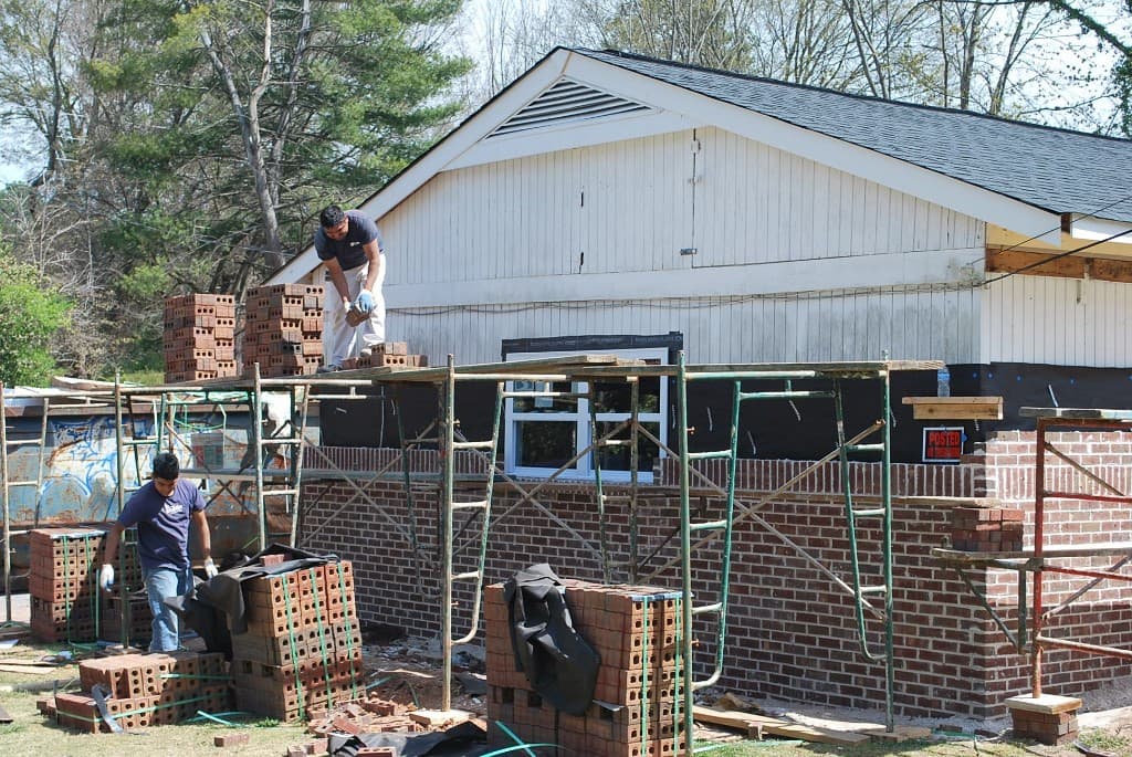 Escobar Masonry team installing a full brick exterior wall while working on scaffolding